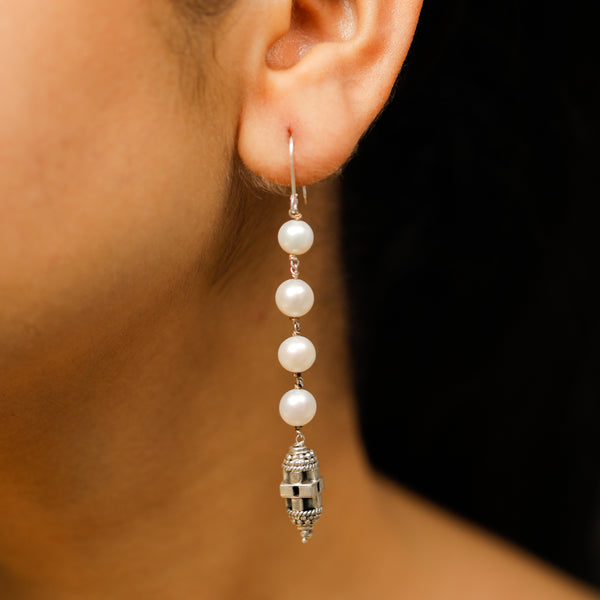 Handcrafted silver earrings with carved bead close-up detailing