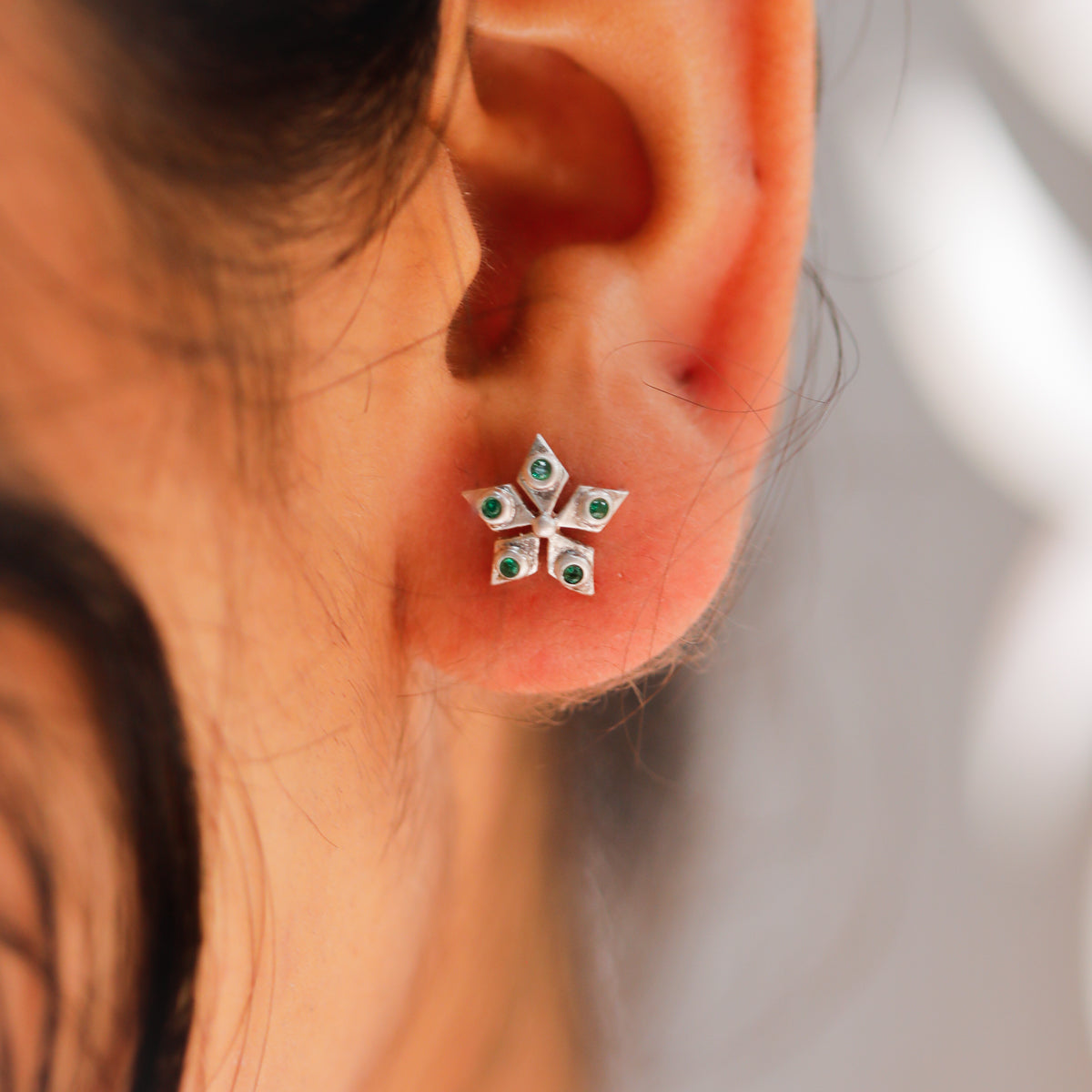 Nakshatra silver stud earrings with green stone accents close-up