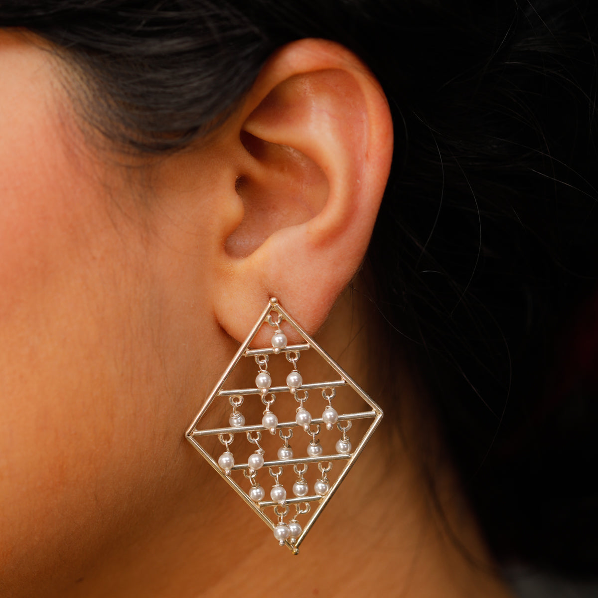 Silver triangle earrings with pearl drops close-up detailing