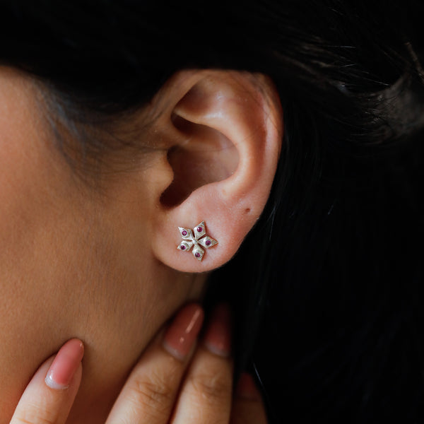 Nakshatra silver stud earrings with ruby-toned accents close-up
