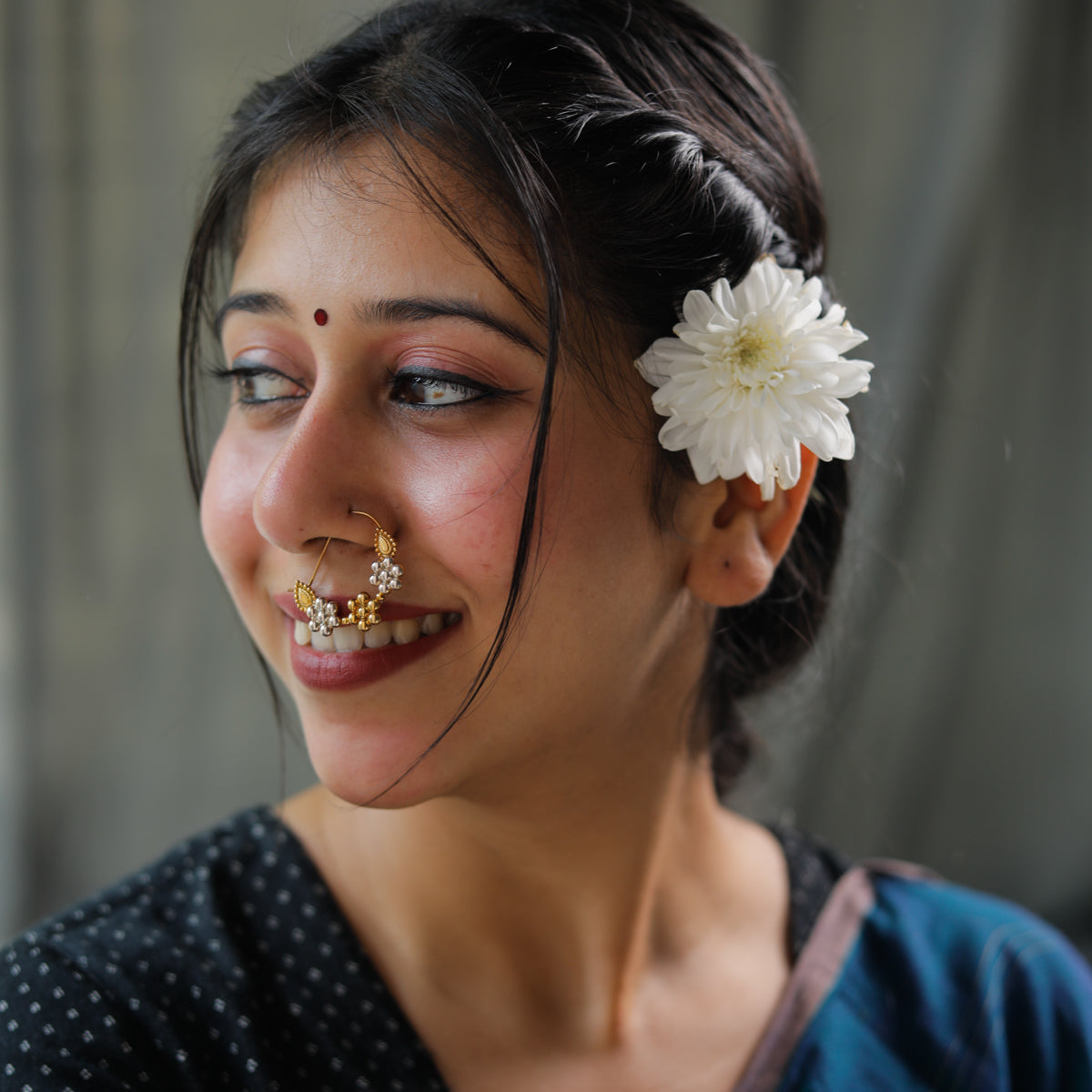 Woman with white flower in hair, traditional jewelry, and smiling face
