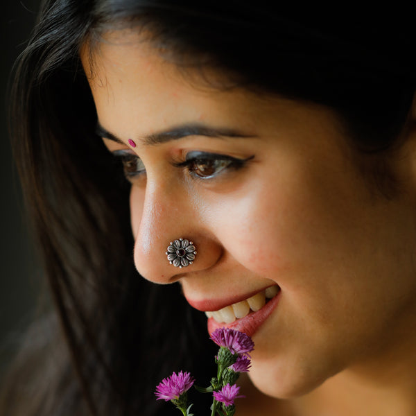 Silver nose pin with red stone on woman's nose