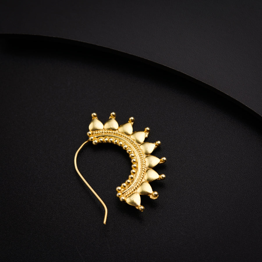 a pair of gold earrings on a black surface