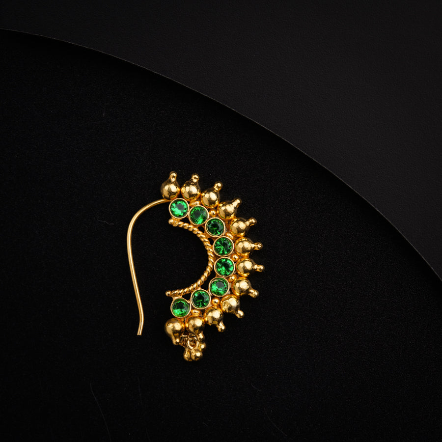 a pair of green and gold earrings on a black surface