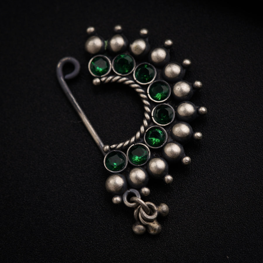 a green and silver brooch sitting on top of a black surface