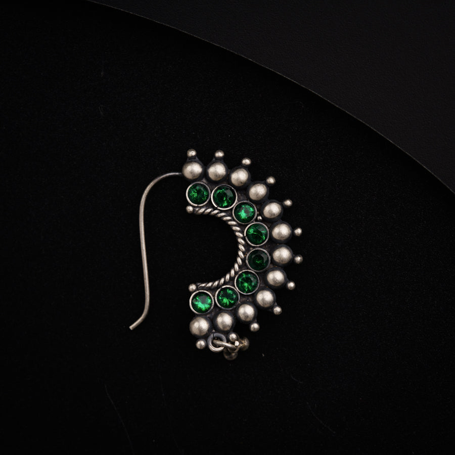a pair of green and silver earrings on a black surface