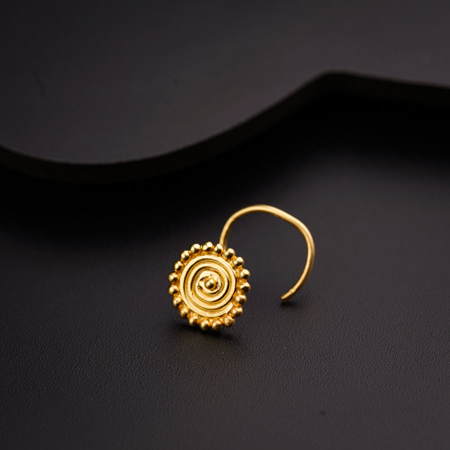 a pair of gold earrings on a black surface