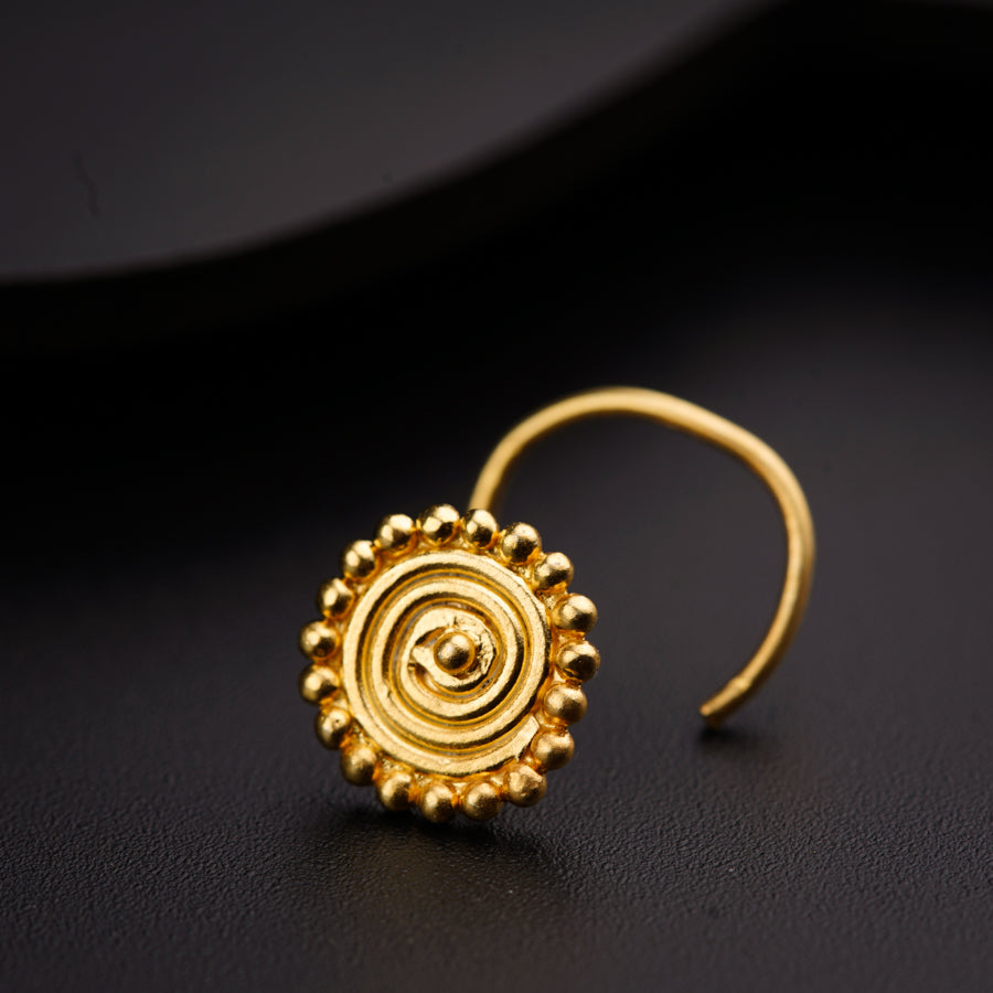 a pair of gold earrings on a black surface