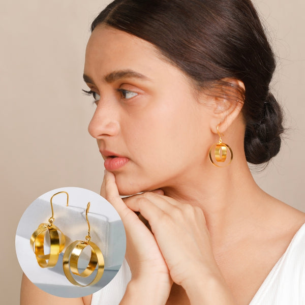 Gold circular drop earrings on a woman