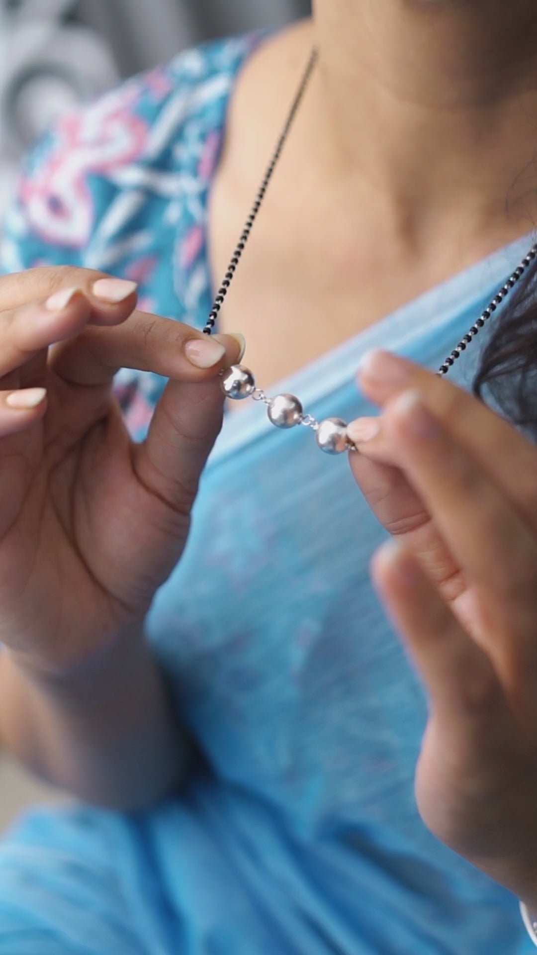 a woman wearing a blue shirt holding a beaded necklace