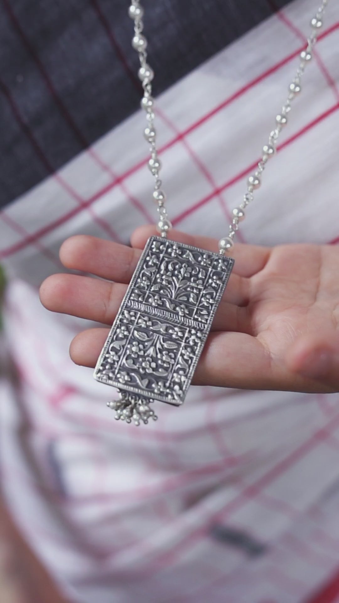 a person is holding a silver necklace in their hand