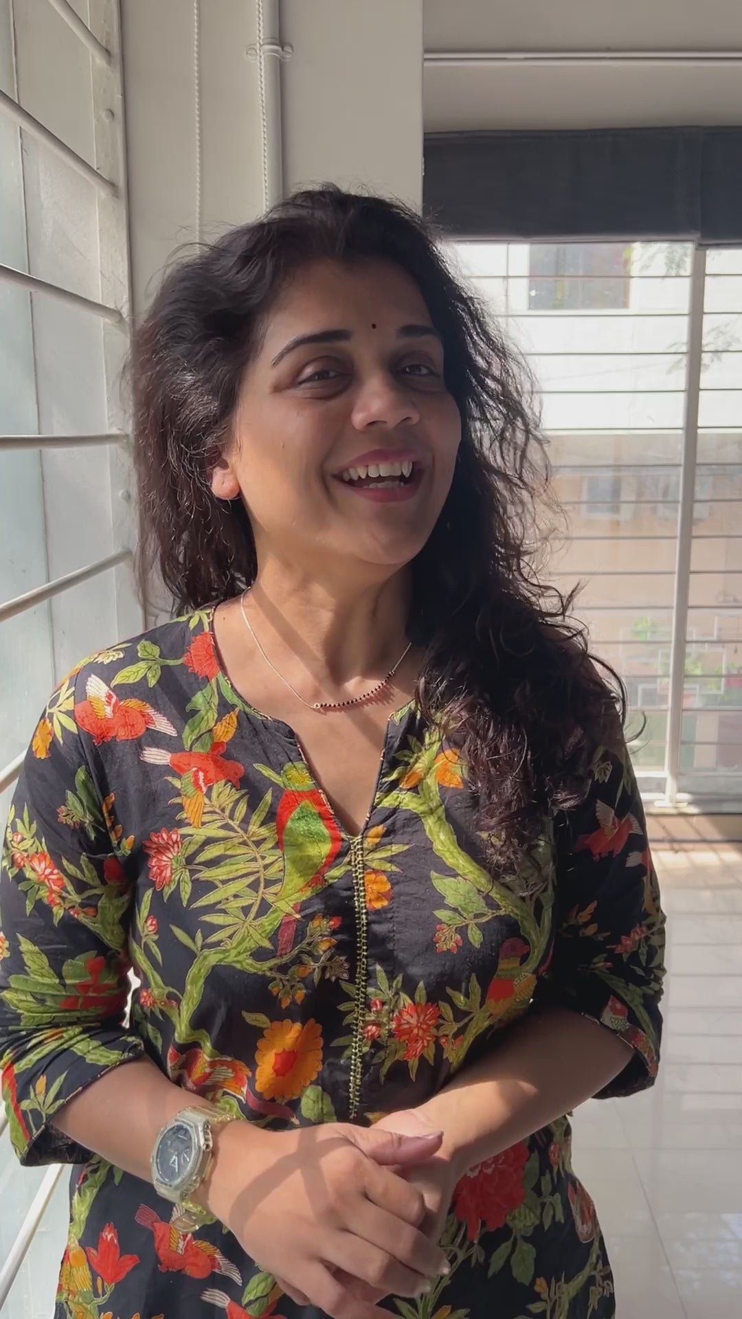 a woman standing in front of a window smiling