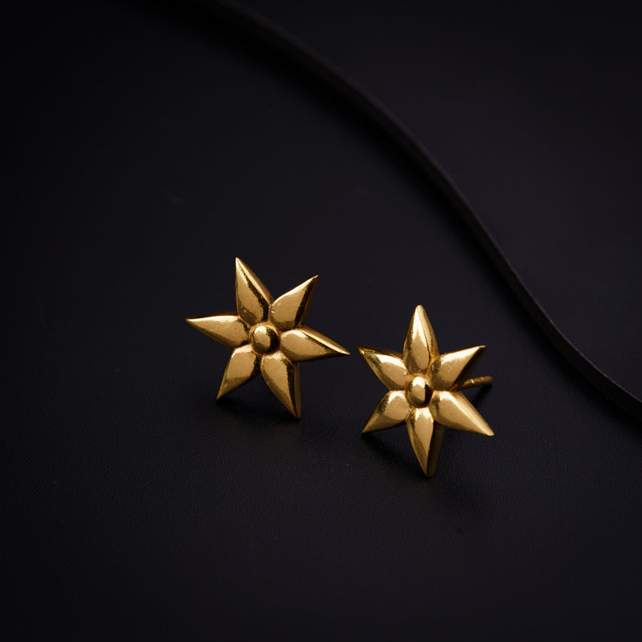a pair of gold earrings on a black surface