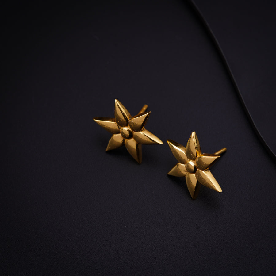 a pair of gold earrings on a black surface