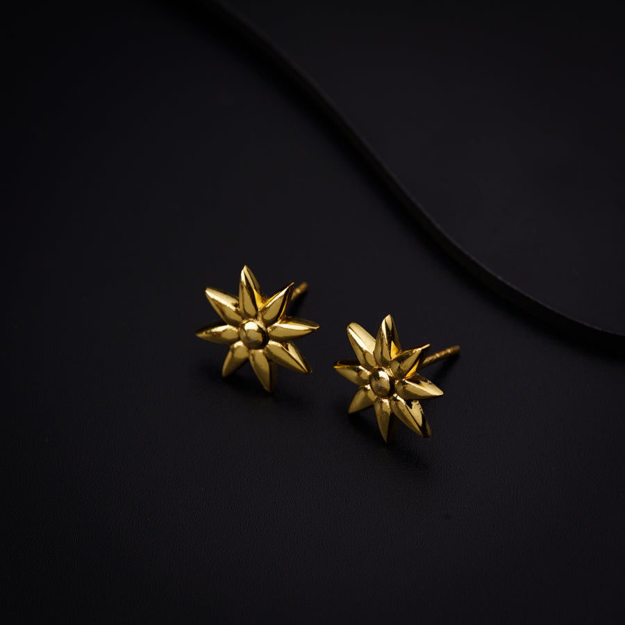 a pair of gold earrings sitting on top of a black surface