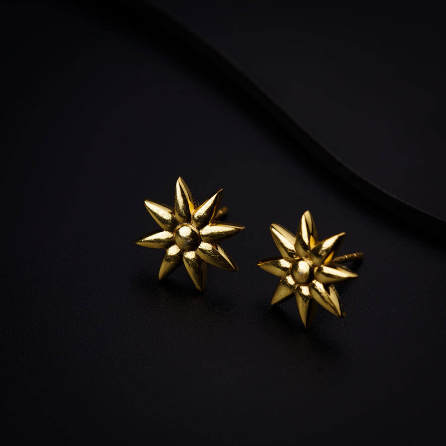 a pair of gold earrings sitting on top of a black surface