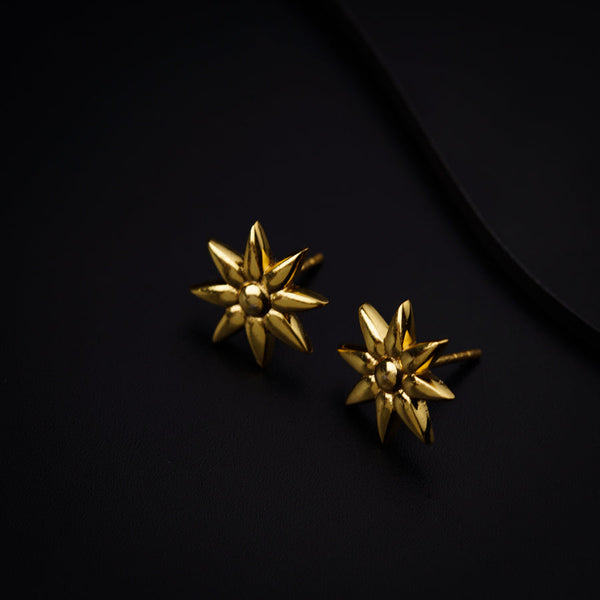 a pair of gold earrings on a black surface