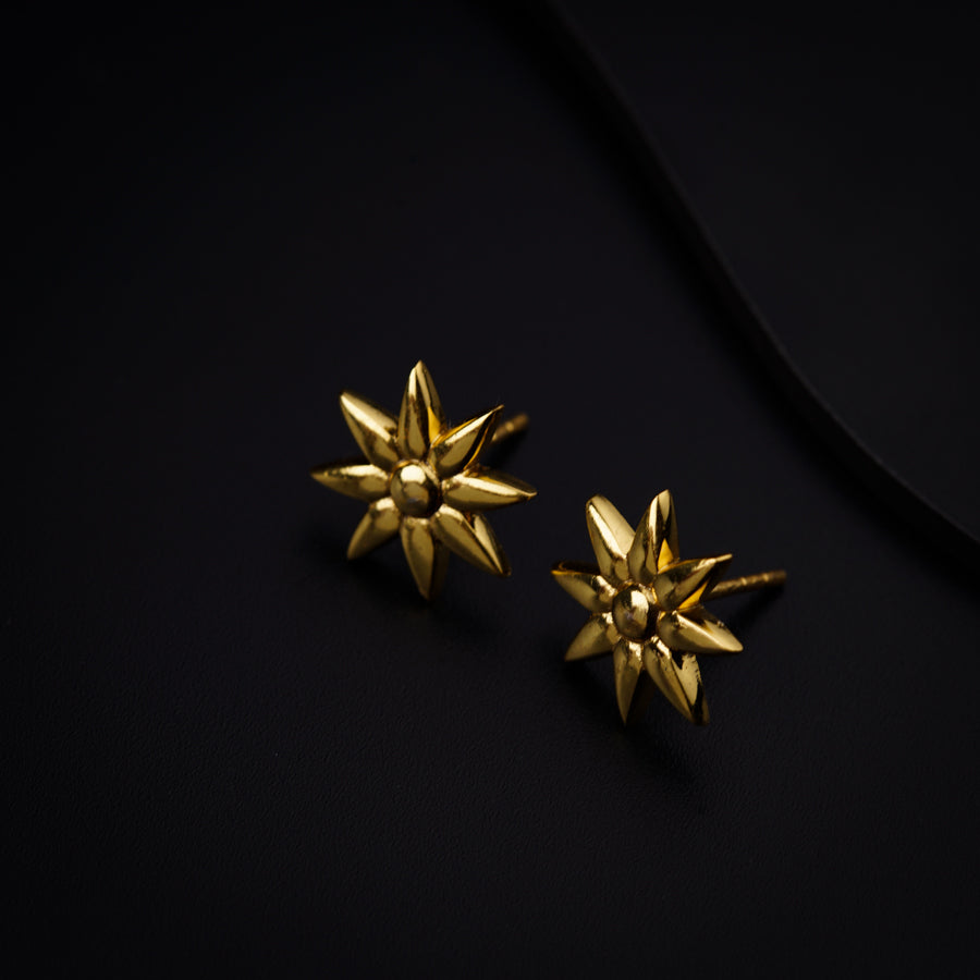 a pair of gold earrings on a black surface