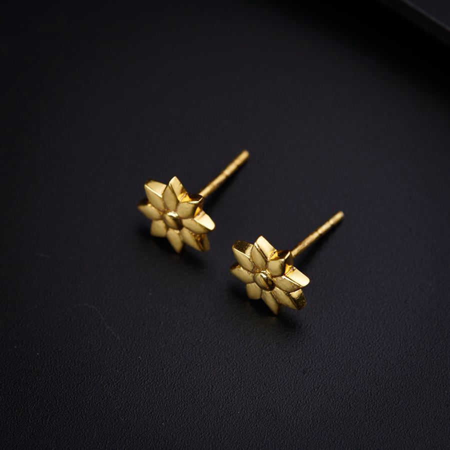 a pair of gold earrings on a black surface
