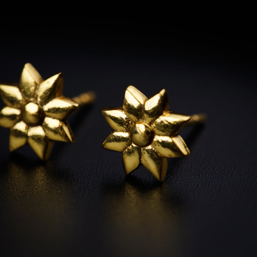 a pair of gold earrings sitting on top of a table