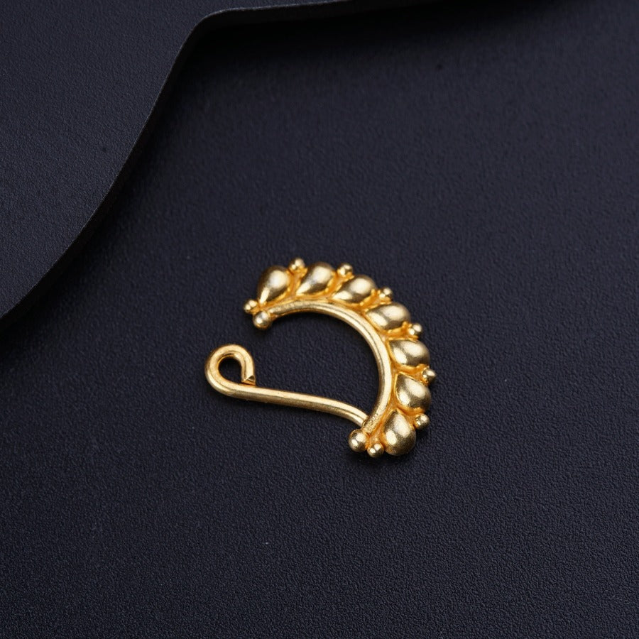 a gold nose ring on a black surface