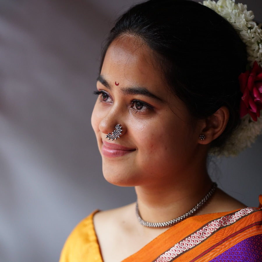 a woman with a nose piercing and a flower in her hair
