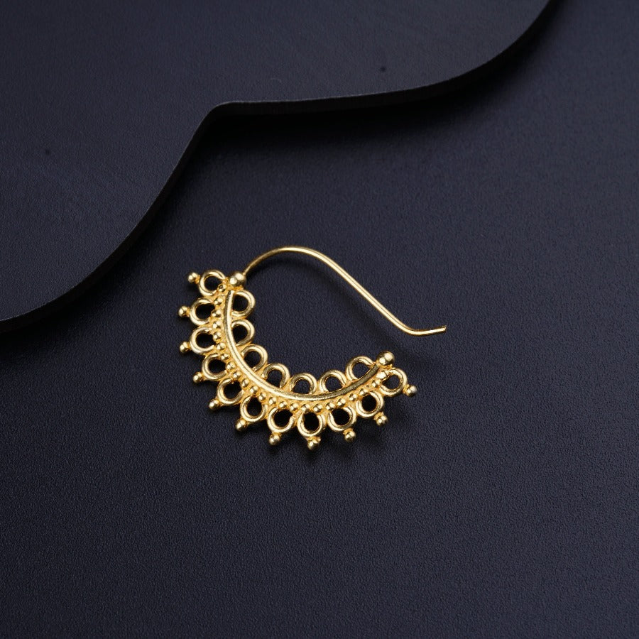a pair of gold earrings on a black surface