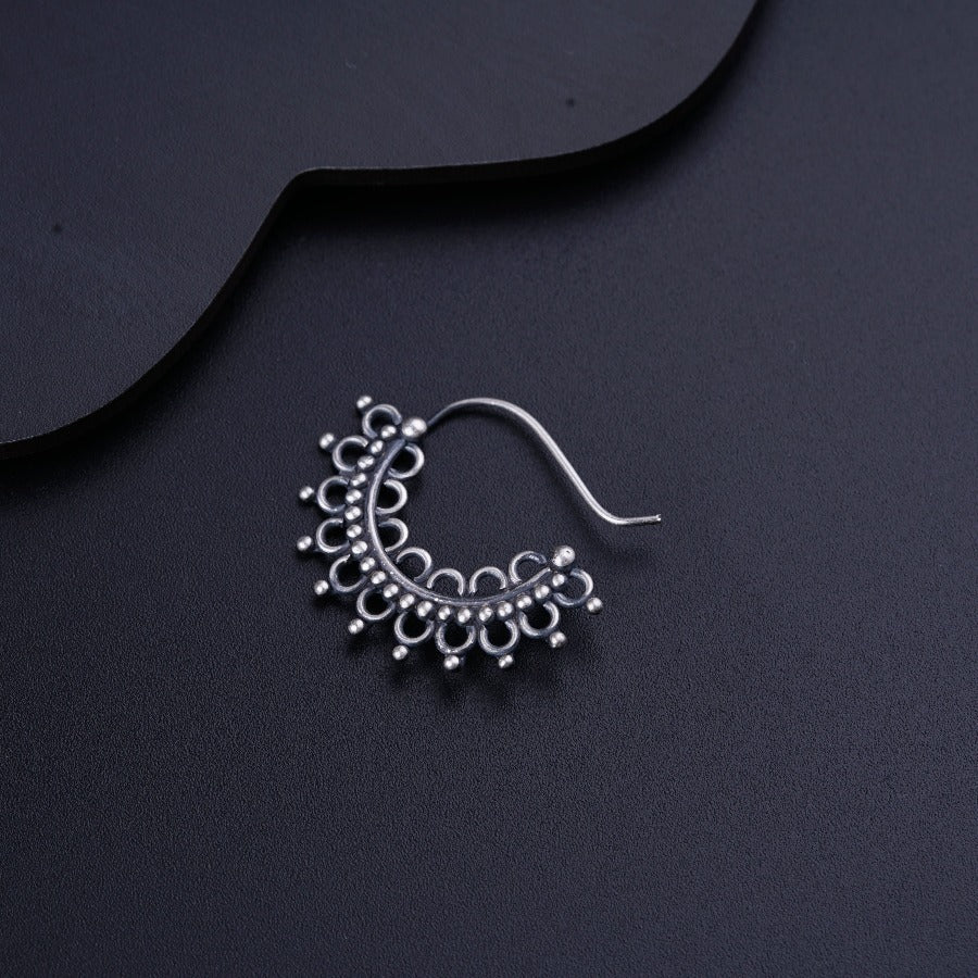 a pair of silver earrings on a black surface