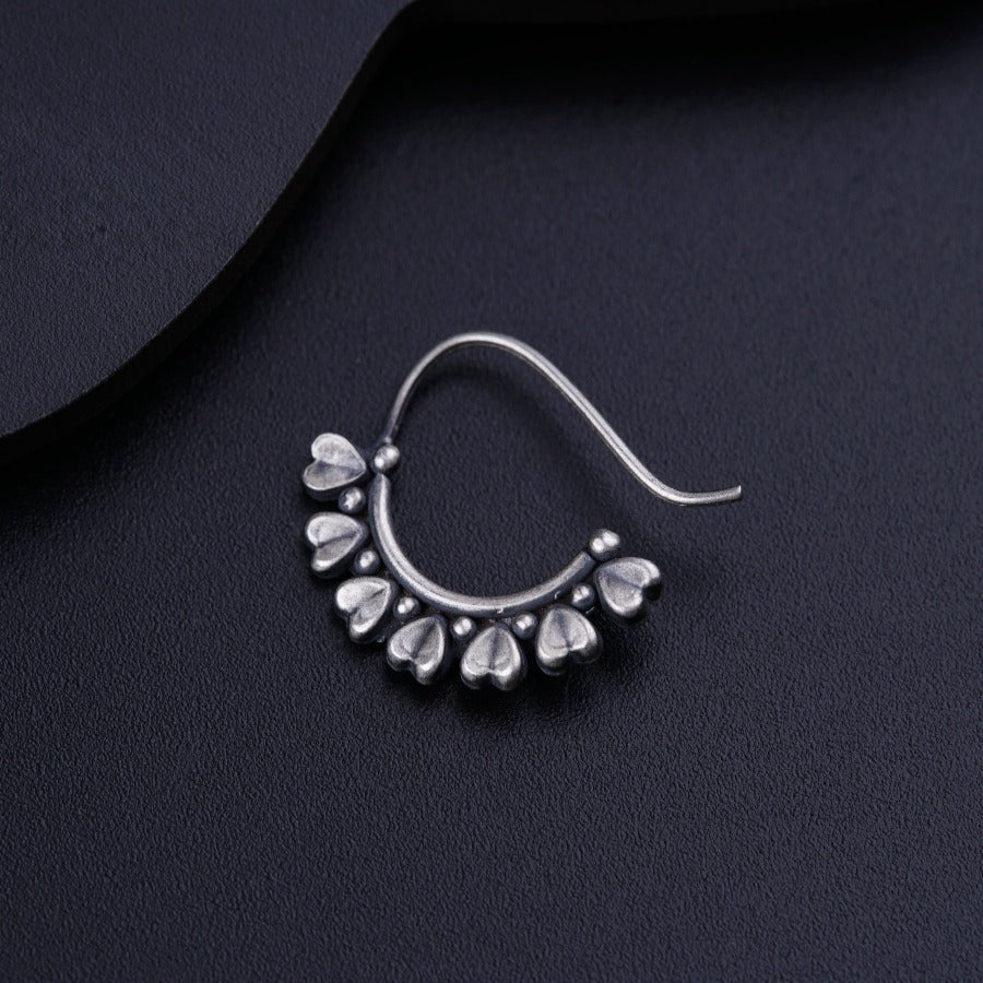 a pair of silver earrings on a black surface