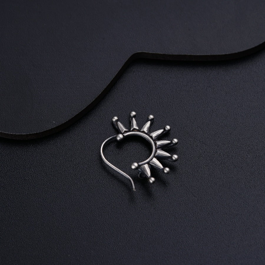 a silver nose ring on a black surface