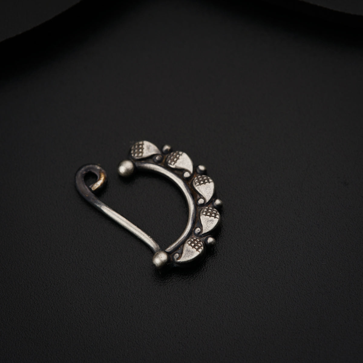 a pair of silver nose rings on a black surface