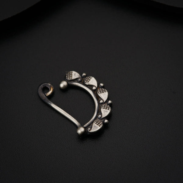 a pair of silver nose rings on a black surface