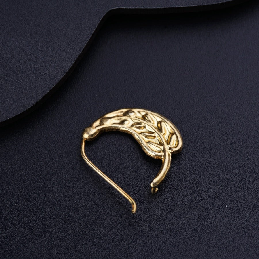 a gold brooch sitting on top of a black surface