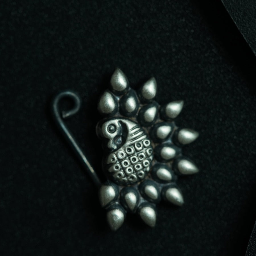 a silver brooch with a bird on it