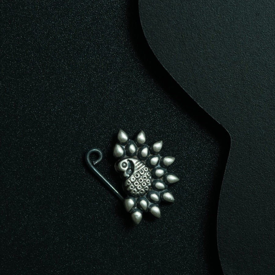 a brooch with a bird on it on a black surface