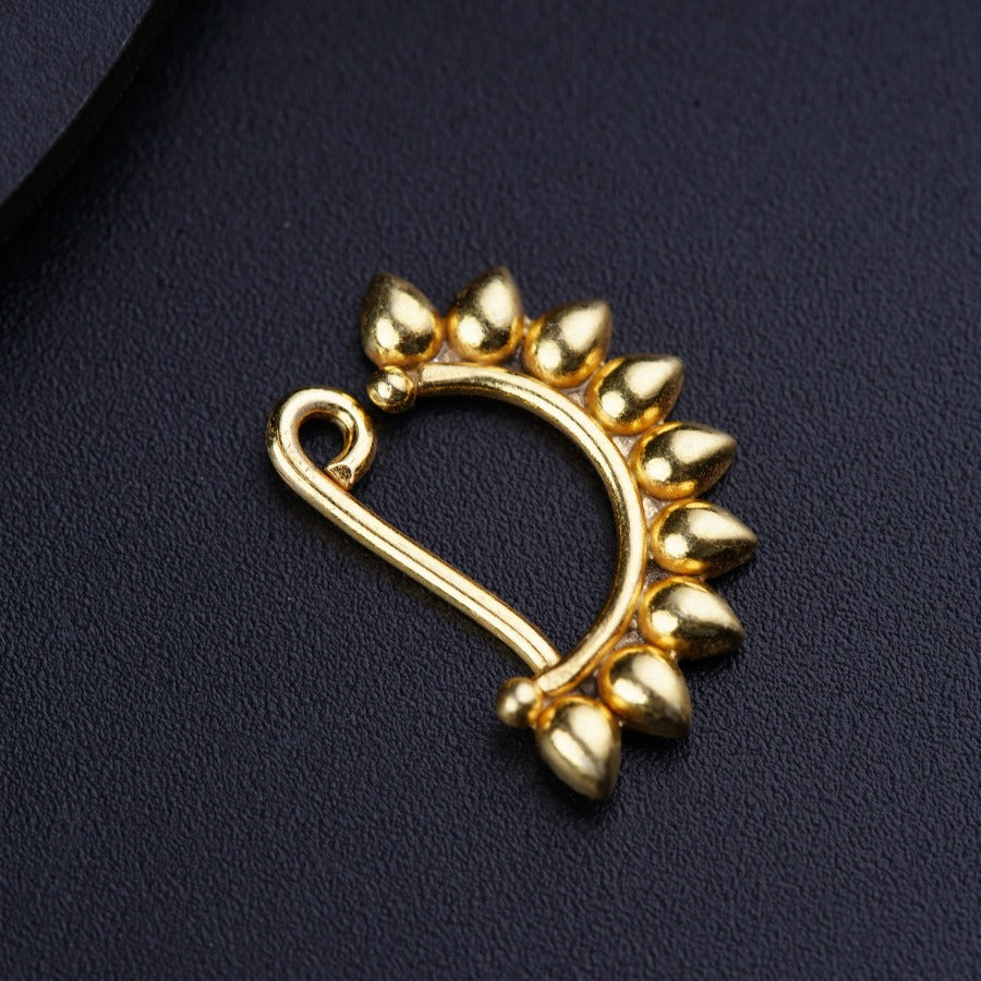 a close up of a gold brooch on a black surface
