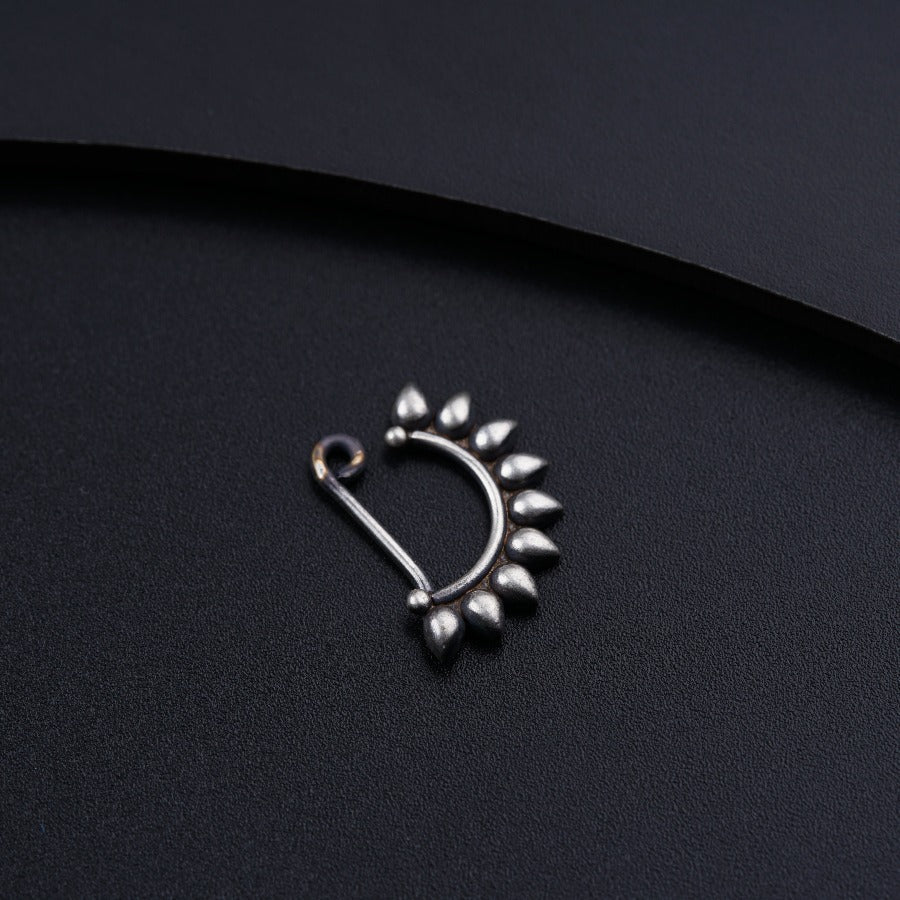 a pair of silver nose rings on a black surface