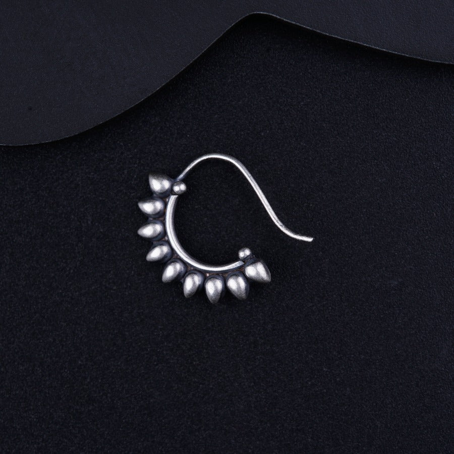 a pair of silver earrings sitting on top of a black surface
