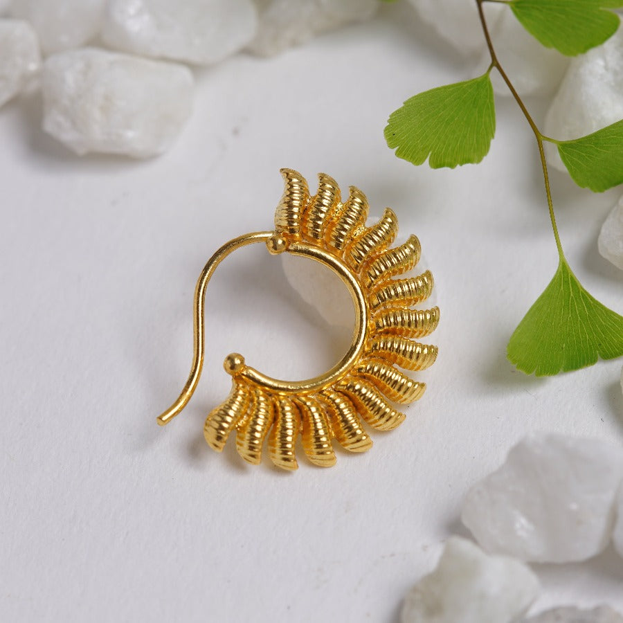 a close up of a gold earring on a white surface