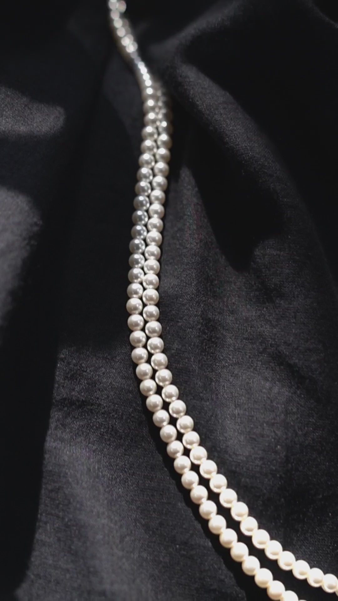 a white pearl necklace on a black cloth