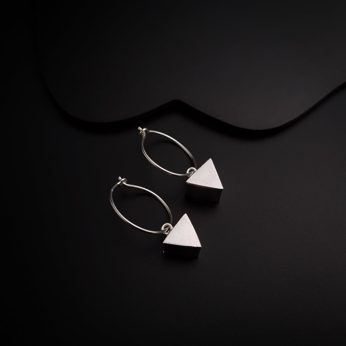 a pair of earrings sitting on top of a black surface