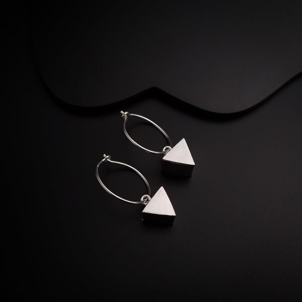 a pair of earrings sitting on top of a black surface