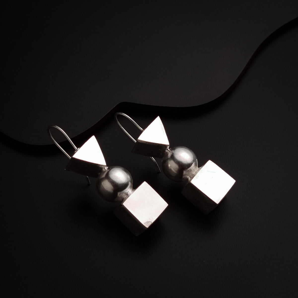 a pair of silver earrings sitting on top of a black surface