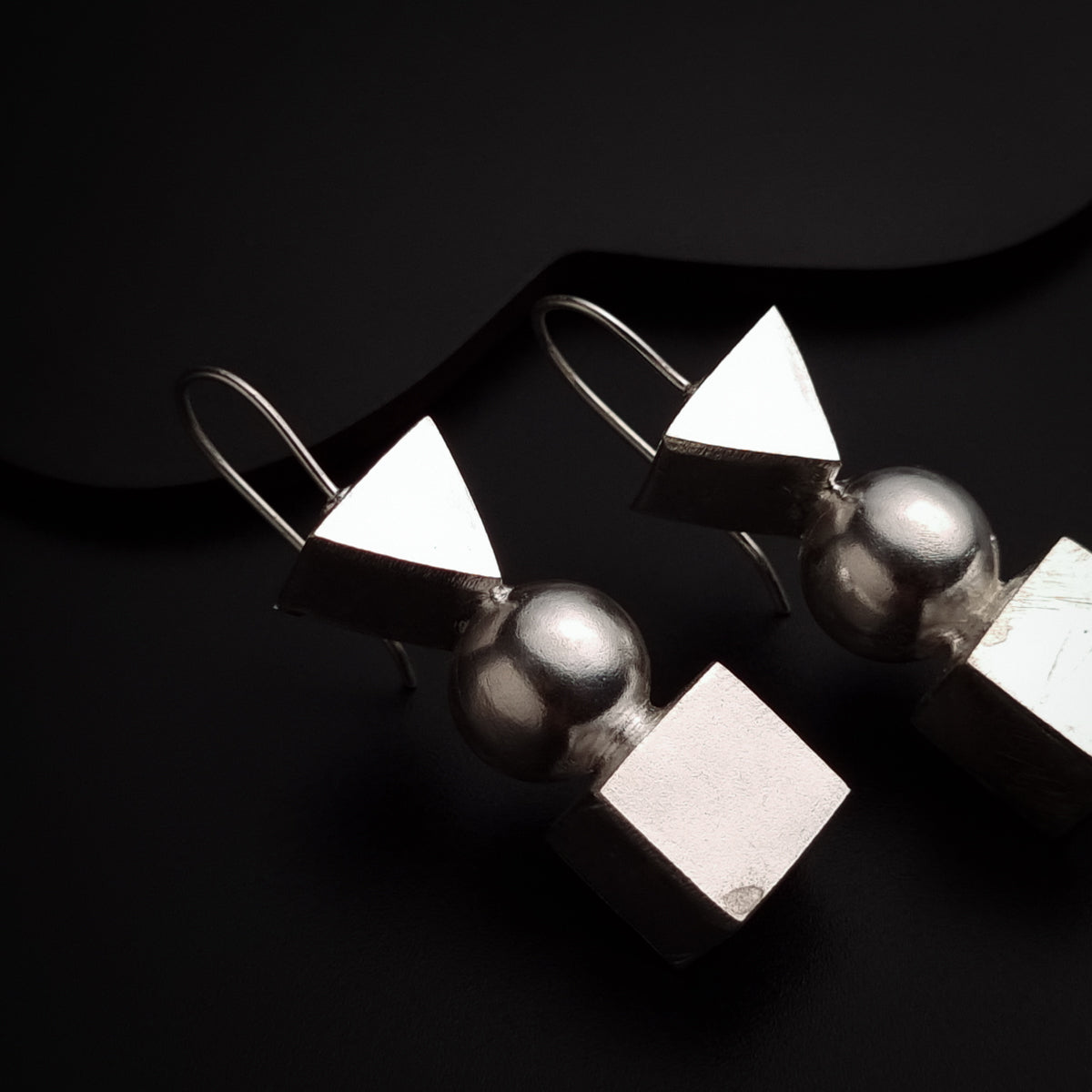 a pair of silver earrings on a black surface