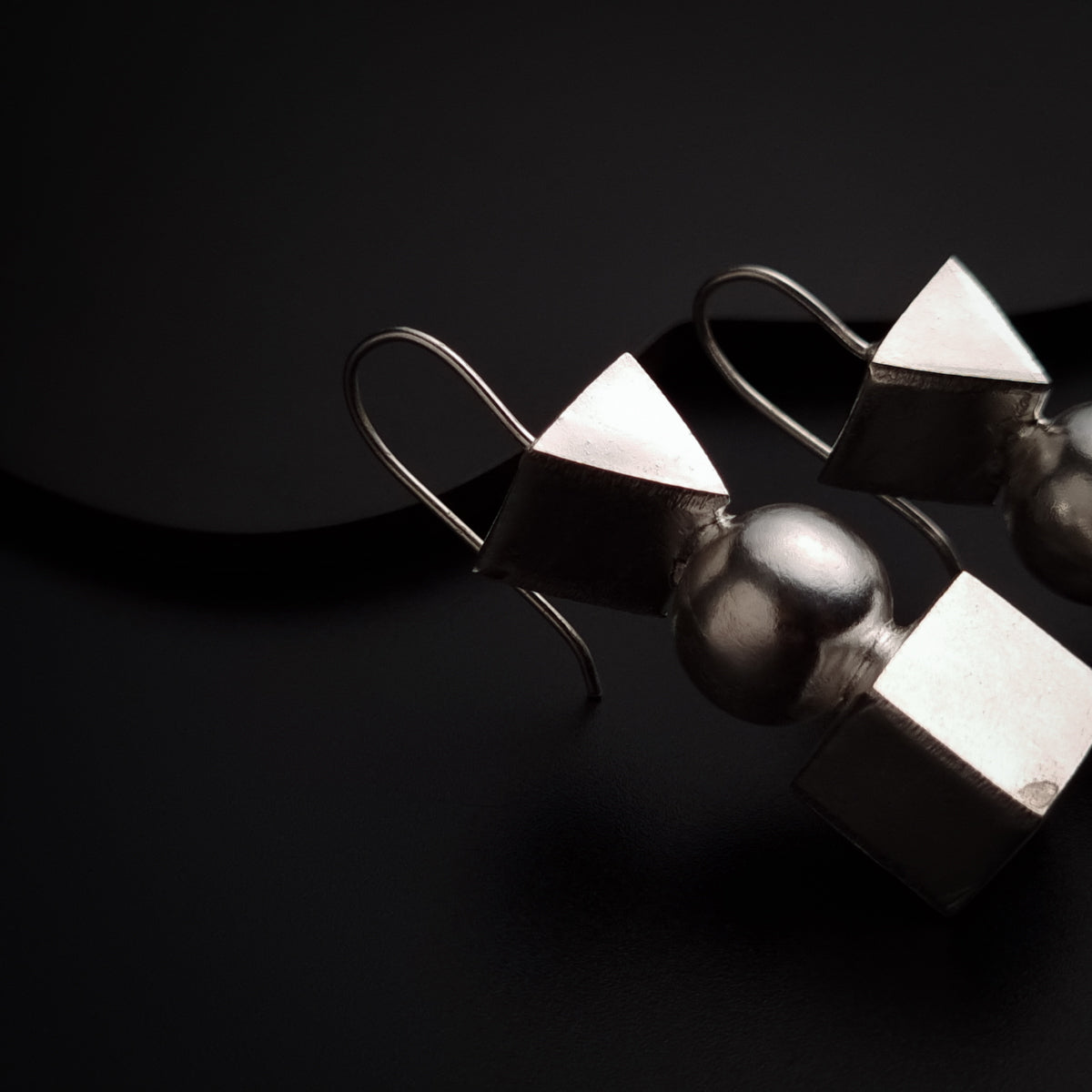a pair of silver earrings sitting on top of a black surface