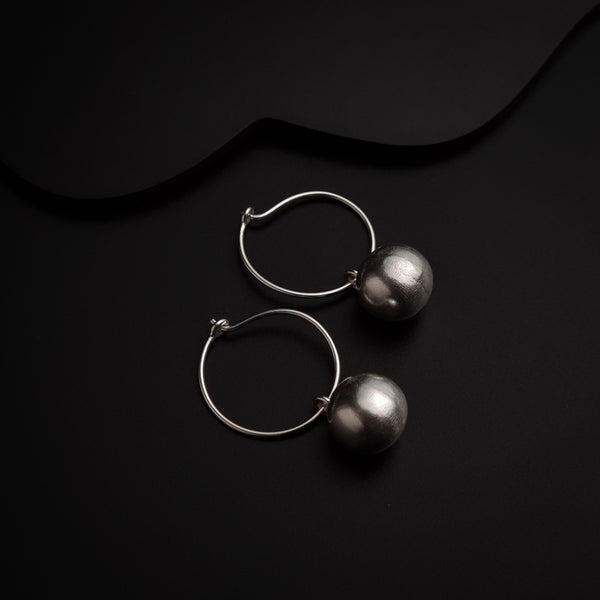 a pair of silver earrings sitting on top of a black surface