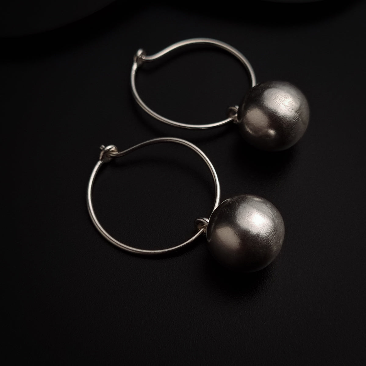 a pair of silver earrings on a black surface