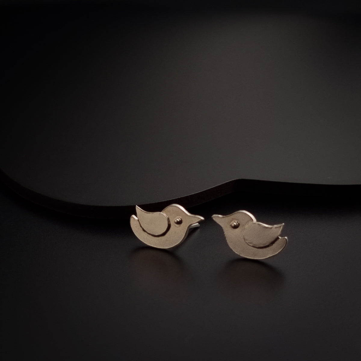 a pair of silver birds sitting on top of a black surface