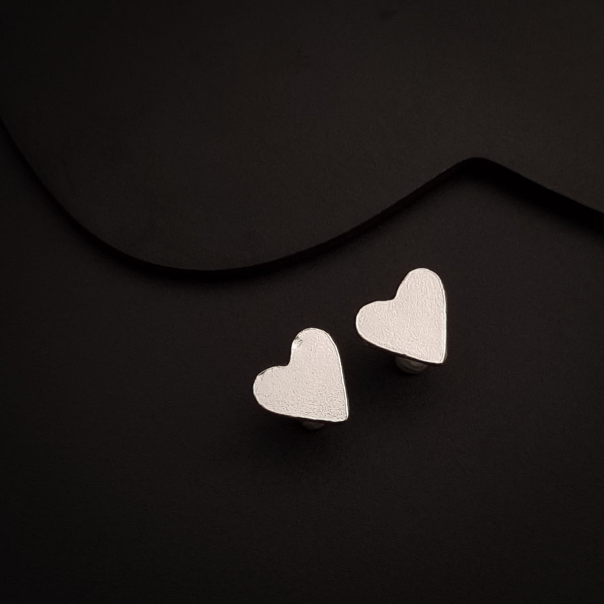 a pair of heart shaped earrings on a black background