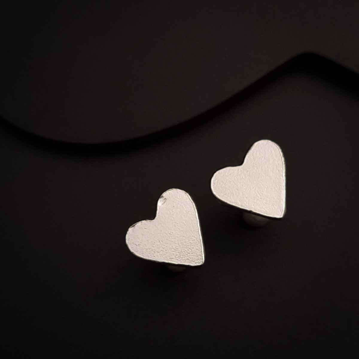 a pair of heart shaped earrings on a black background